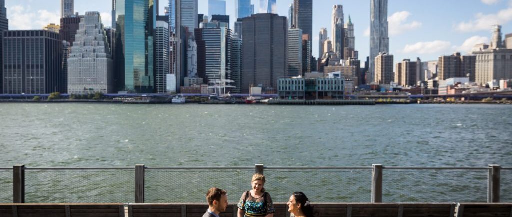 Couple saying vows in front of NYC waterfront for an article on how to get married in Brooklyn Bridge Park