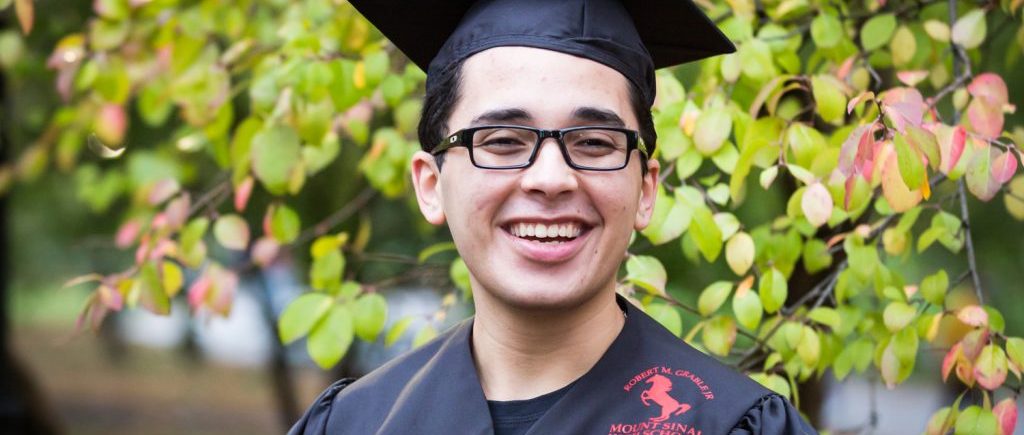 Young man wearing graduation cap and gown during a Central Park senior portrait session