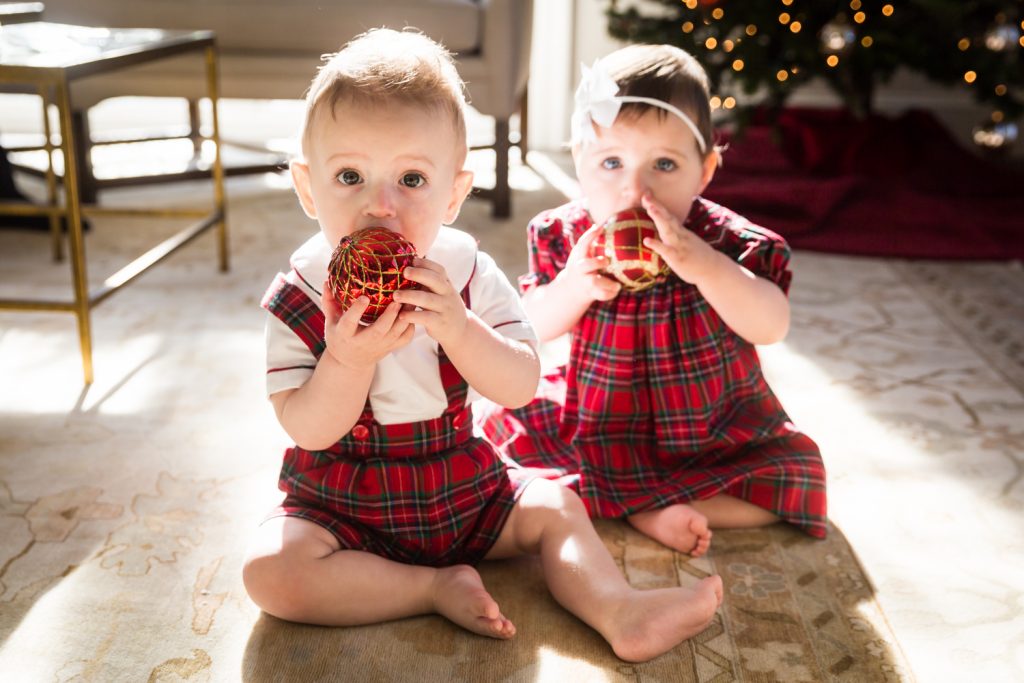 Two babies chewing on Christmas ornaments for an article on holiday family portrait ideas