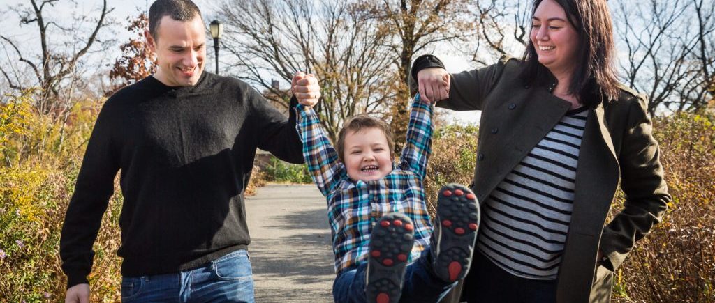 Parents swinging little boy by his arms for an article about a Forest Park photo shoot neighborhood discount offer