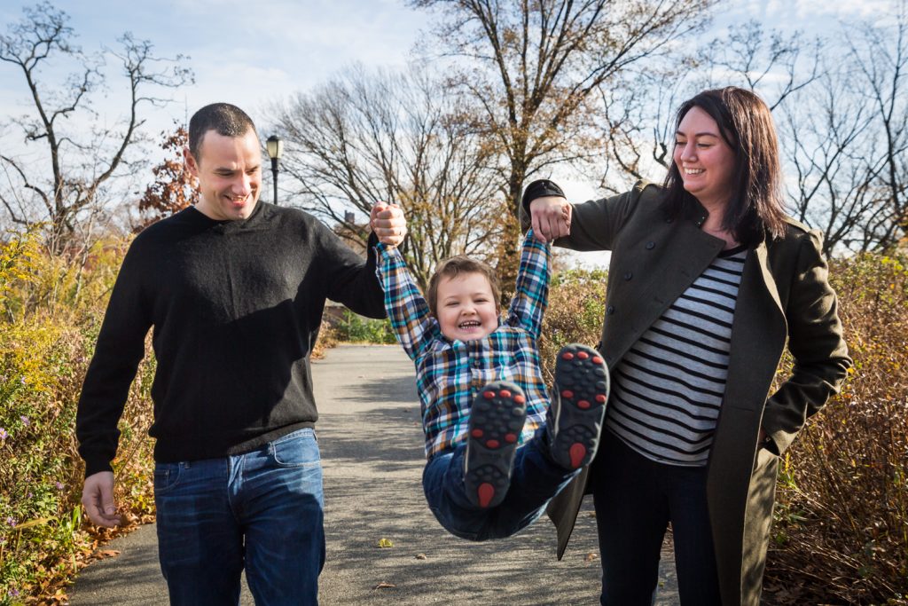 Parents swinging little boy by his arms for an article about a Forest Park photo shoot neighborhood discount offer
