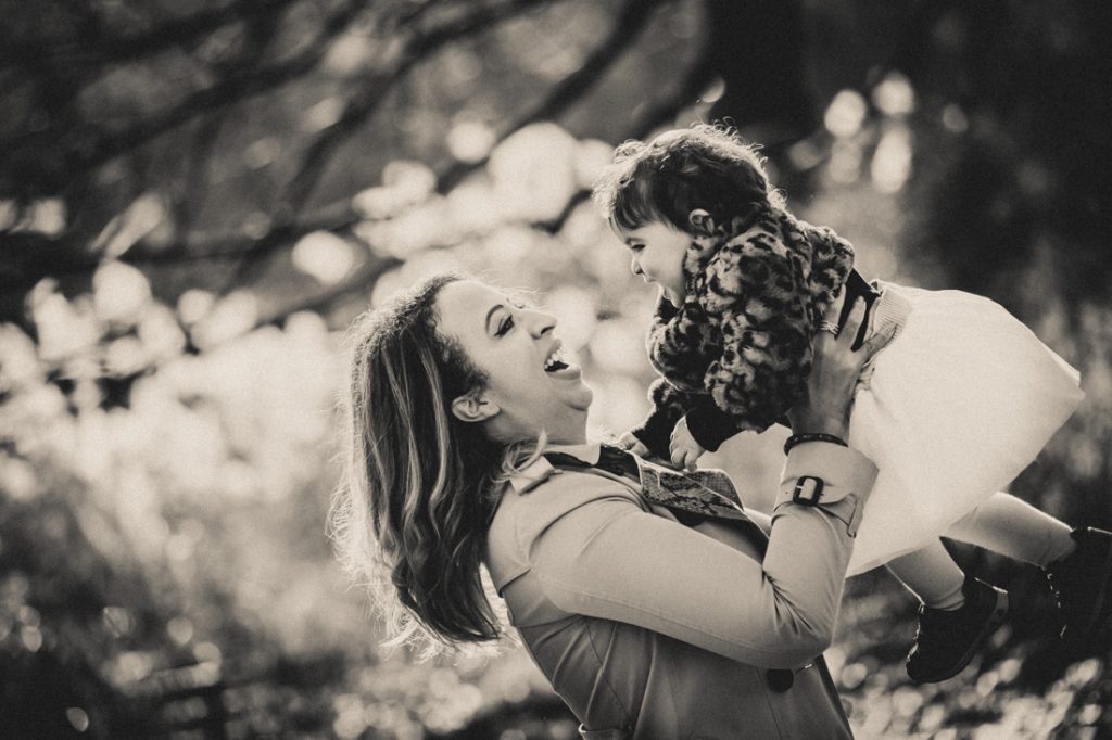 Black and white photo of mother lifting up little girl