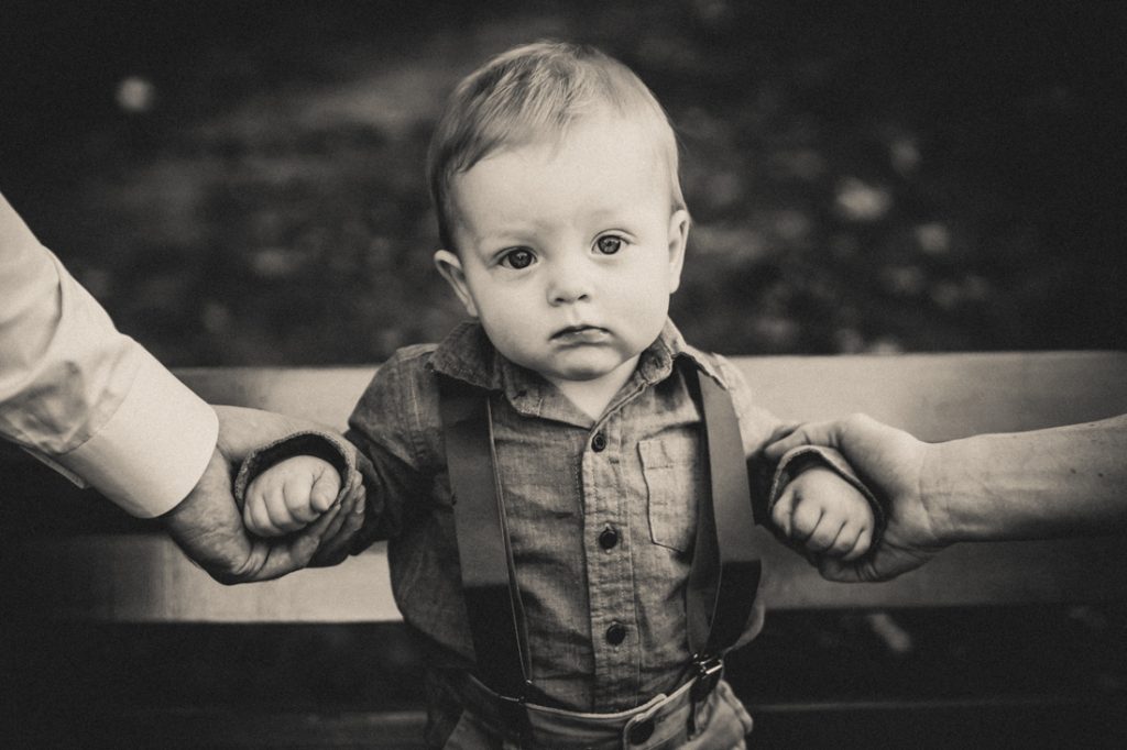 Black and white photo of little boy being held by arms