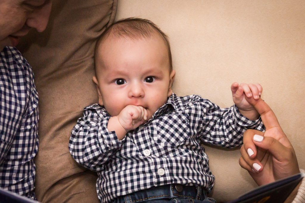 Baby boy chewing hand on brown couch