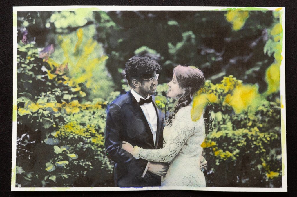 Hand-colored image of bride and groom hugging in garden
