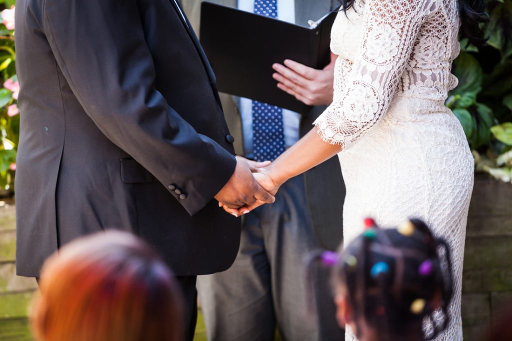 Close up of bride and groom holding hands