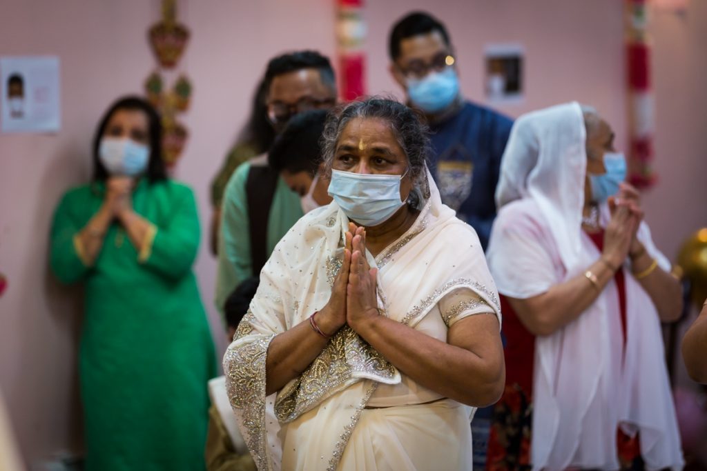 Woman wearing white sari praying with folded hands