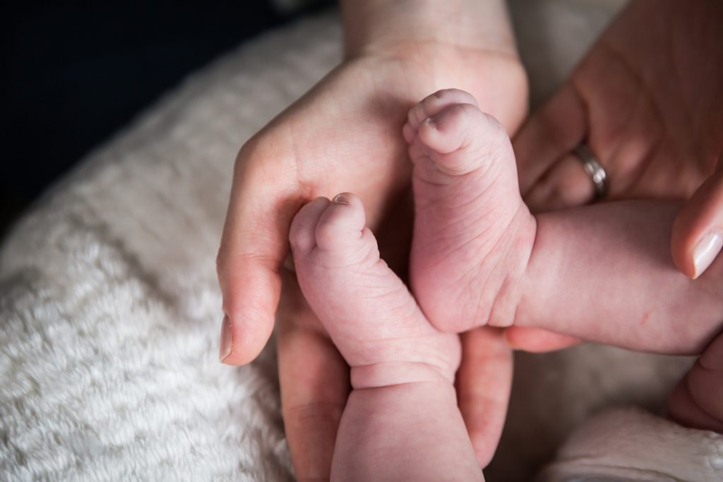 Mother's hand holding newborn baby feet