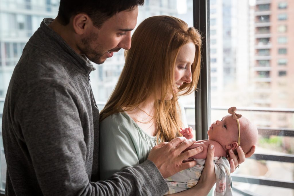 Upper West Side newborn portrait of parents holding baby in front of window