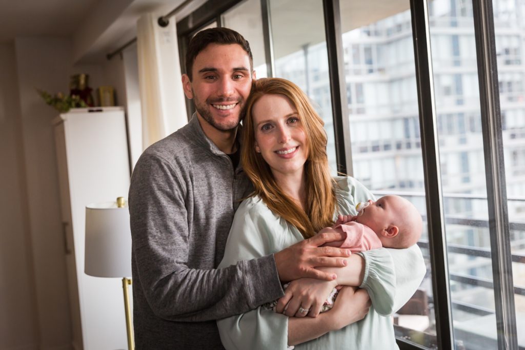Upper West Side newborn portrait parents holding baby in front of window