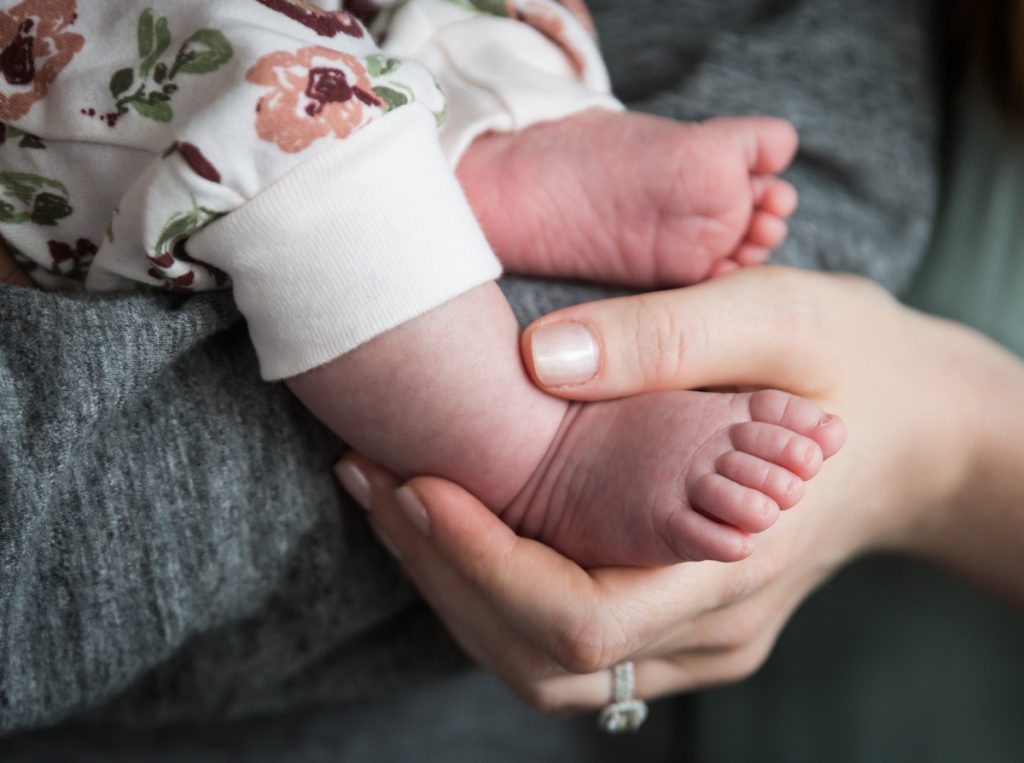 Mother's hand holding newborn baby's feet