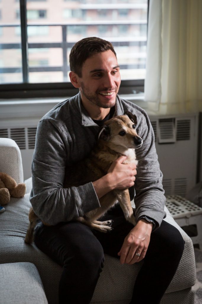 Man holding dog while sitting on couch