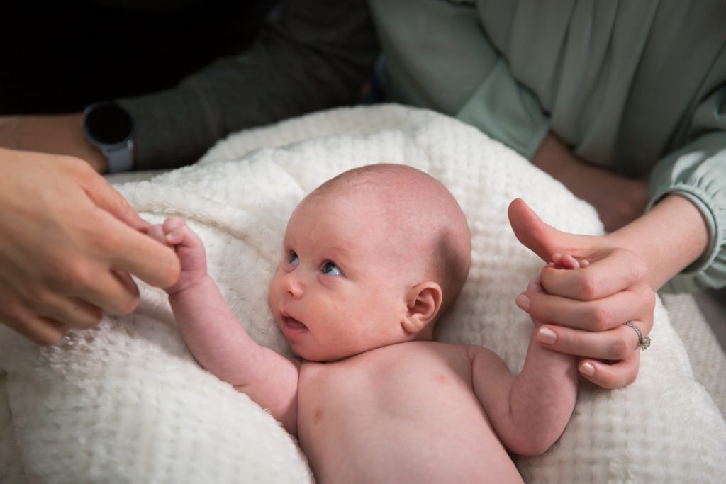 Parents holding newborn baby's hands