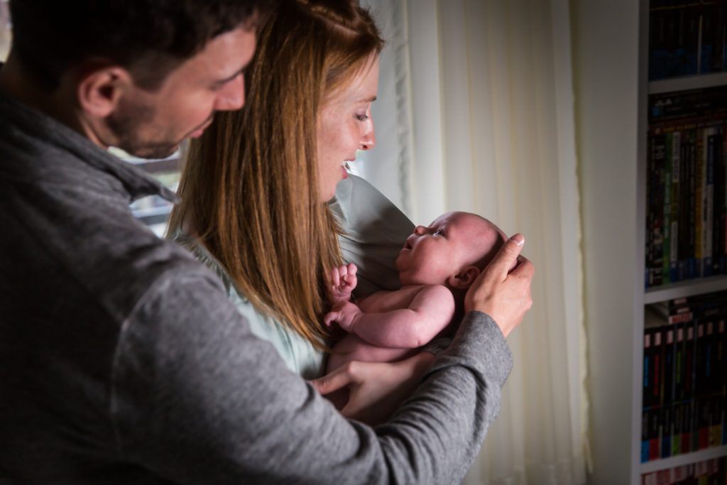 Parents cuddling with newborn baby in apartment
