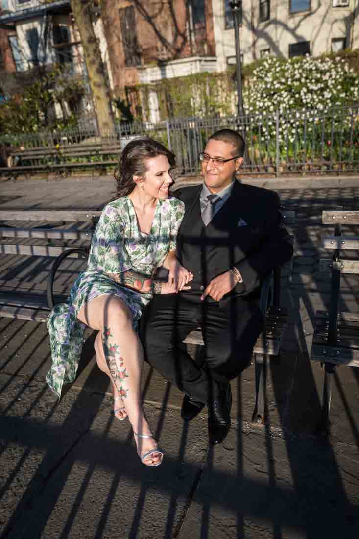 Couple seated on bench with shadows during a Brooklyn Heights Promenade engagement photo shoot