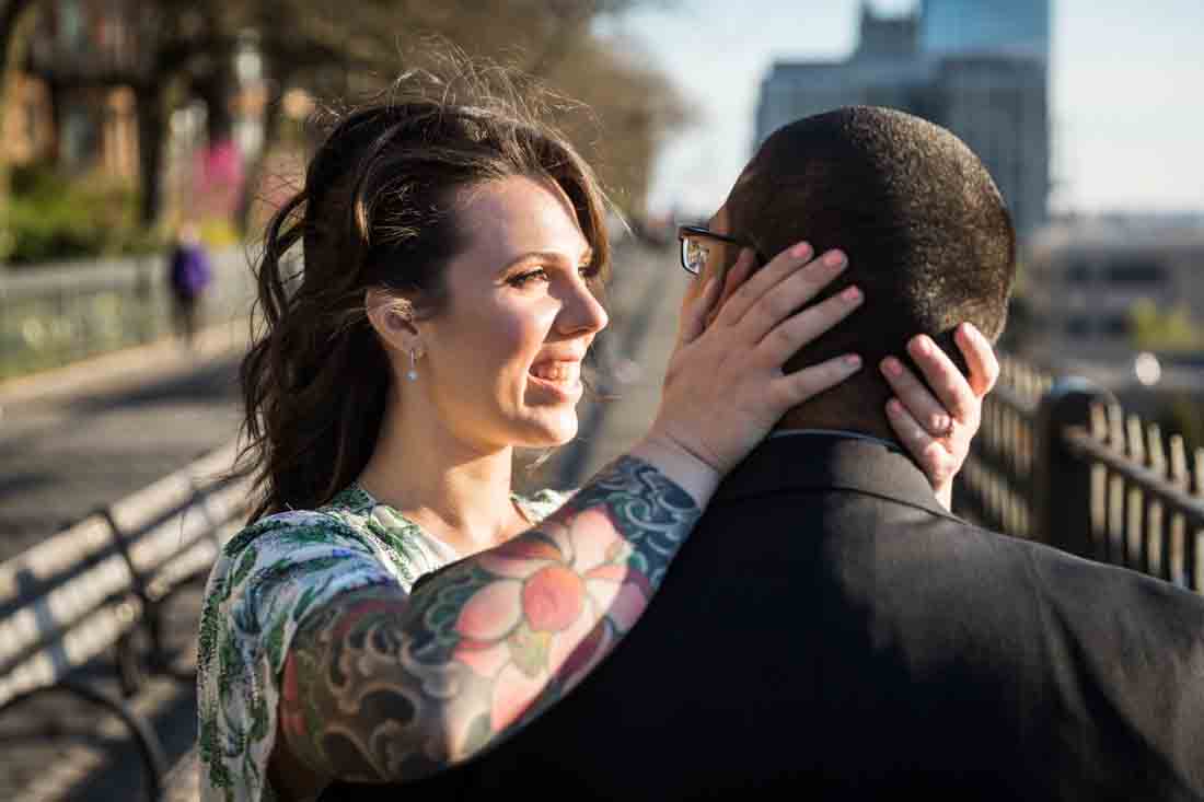 Woman holding man's head during a Brooklyn Heights Promenade engagement photo shoot