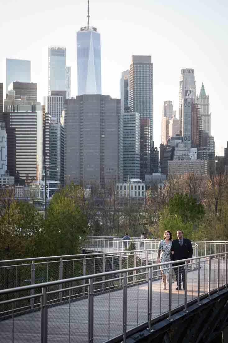 Couple walking up walkway in front of Manhattan skyline