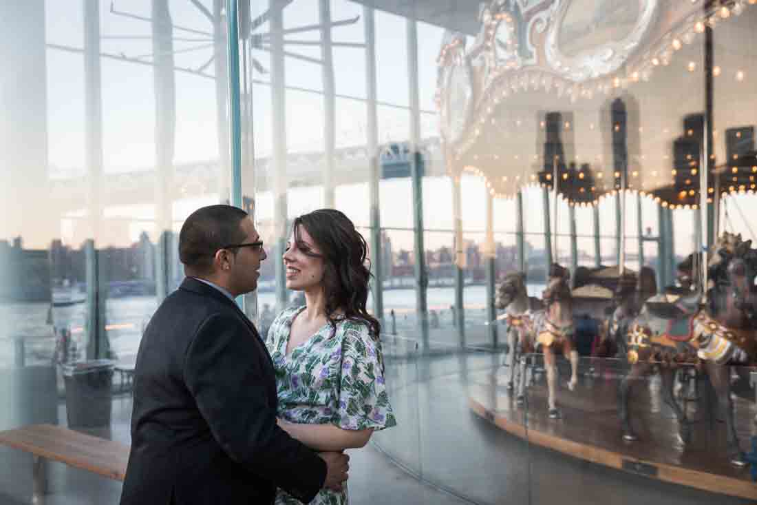 Couple leaning against glass window in front of Jane's Carousel