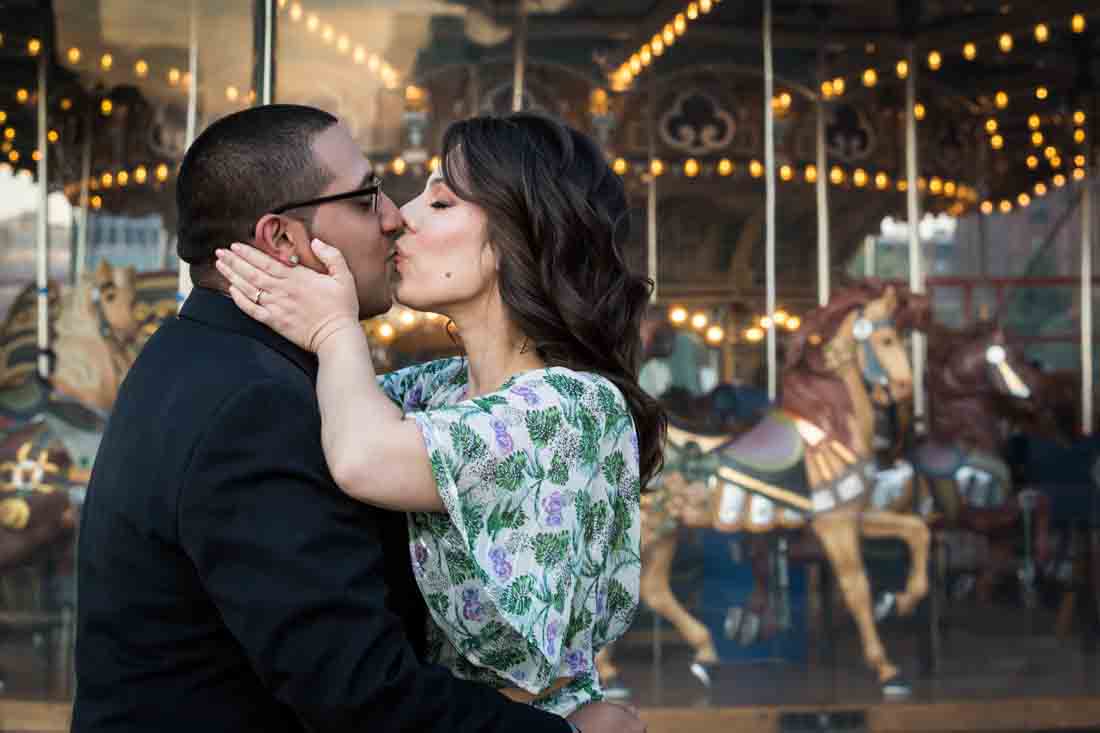Couple kissing in front of Jane's Carousel during Brooklyn Bridge Park engagement shoot