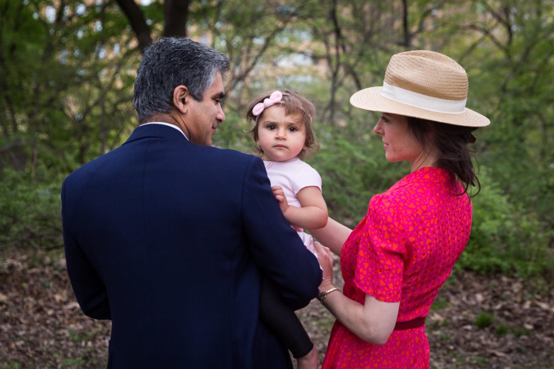 Parents holding a little girl in Central Park for an article on NYC family portrait location ideas
