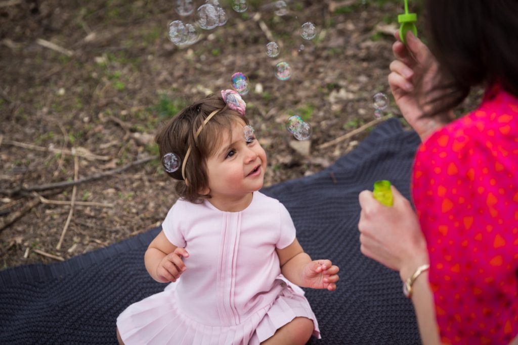 Little girl wearing a pink dress looking at bubbles