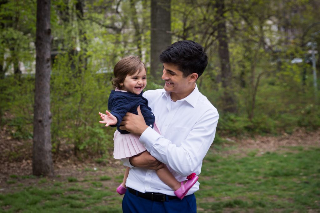 Young man holding little girl in his arms in Central Park