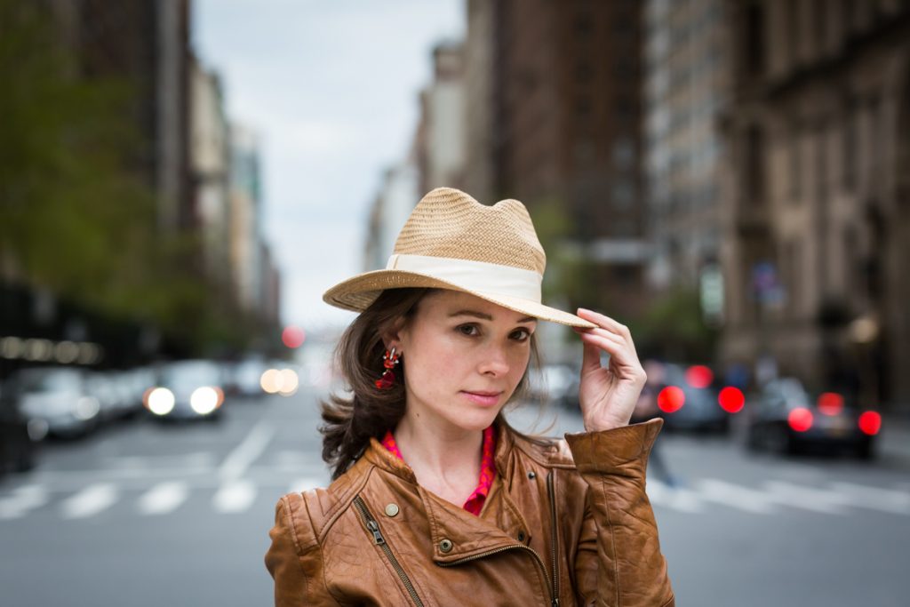 Woman holding on to brim of hat for an article on NYC family portrait location ideas