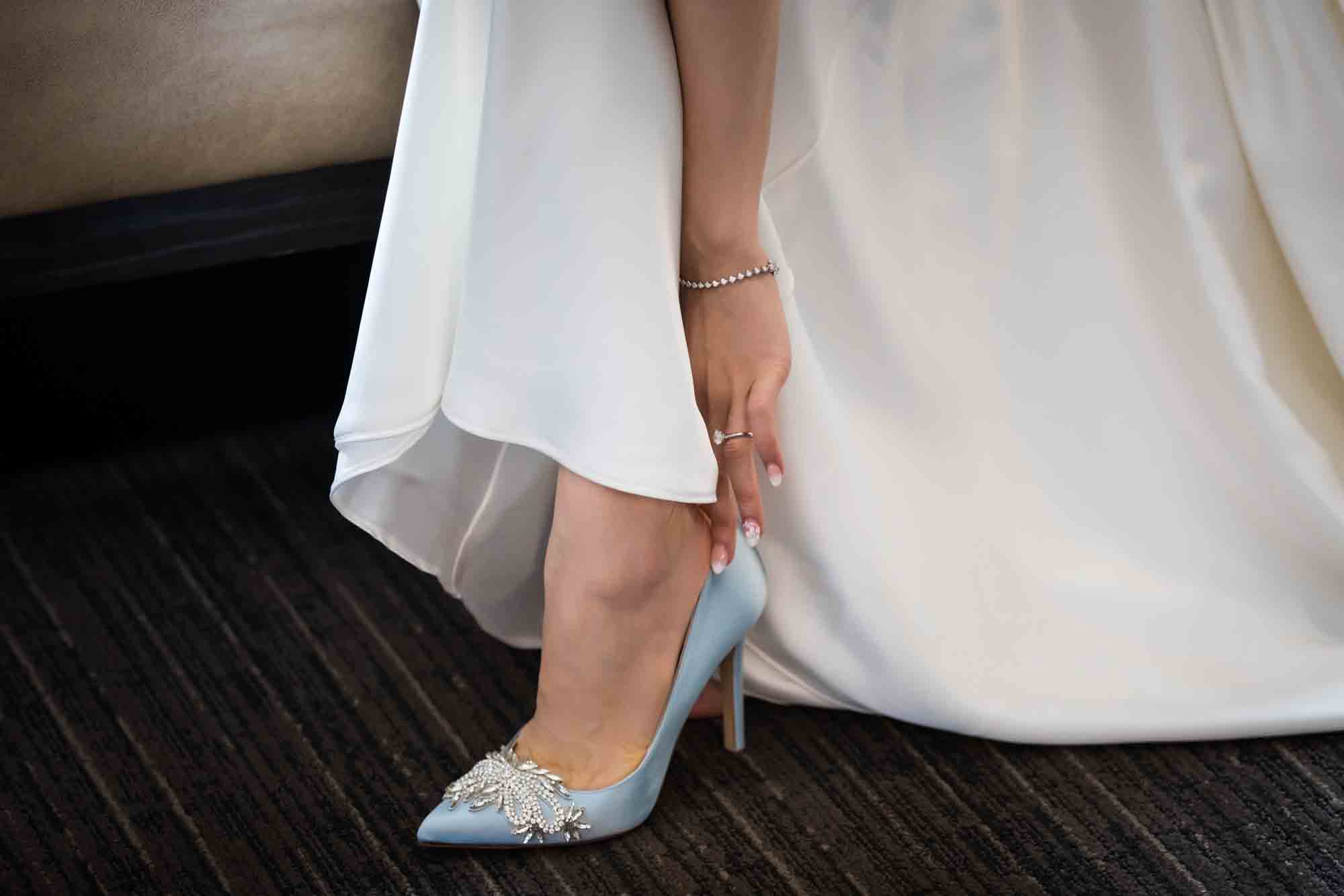 Bride's hand adjusting light blue high heel shoe