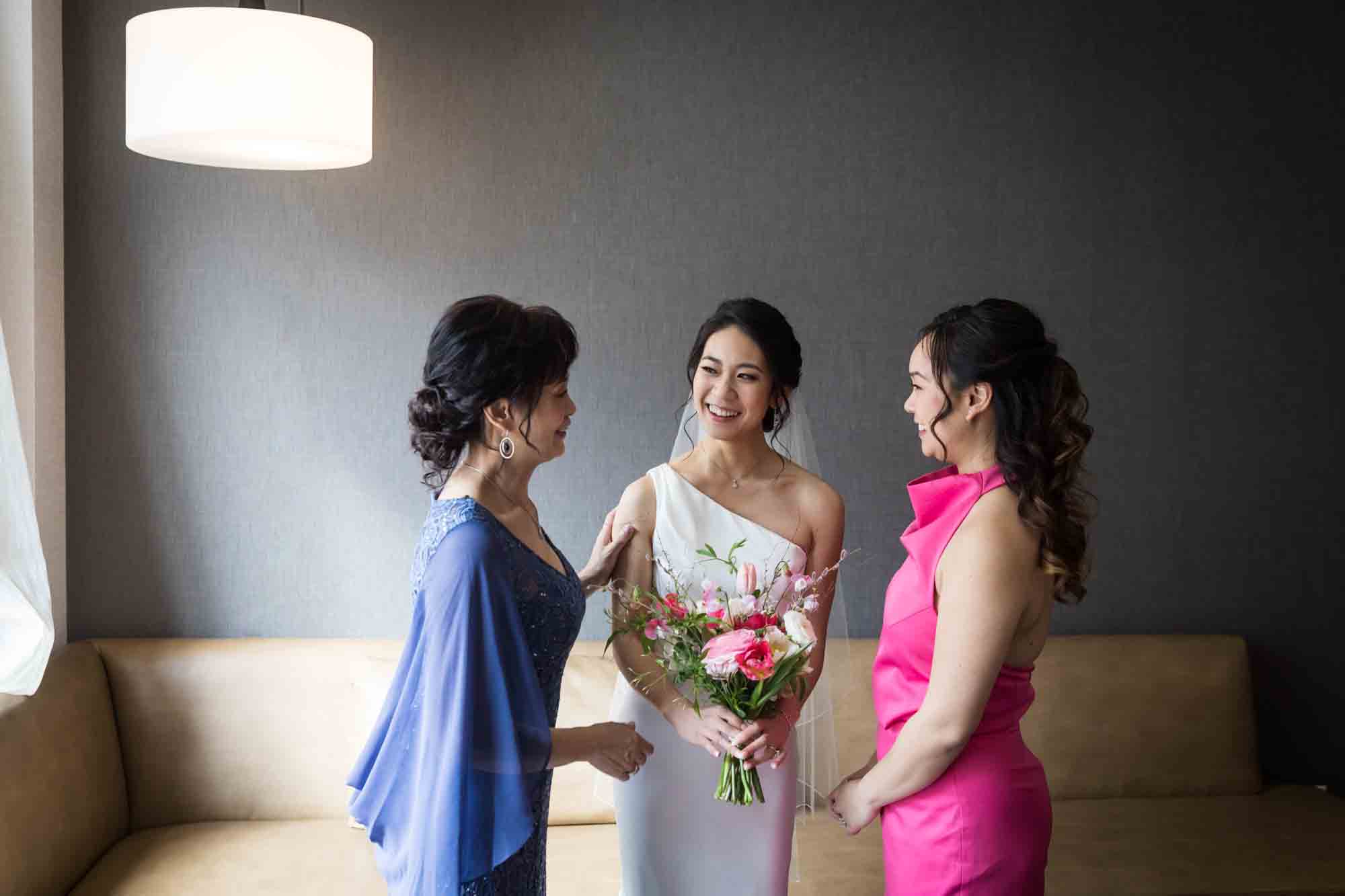 Bride laughing with mother and sister before her wedding