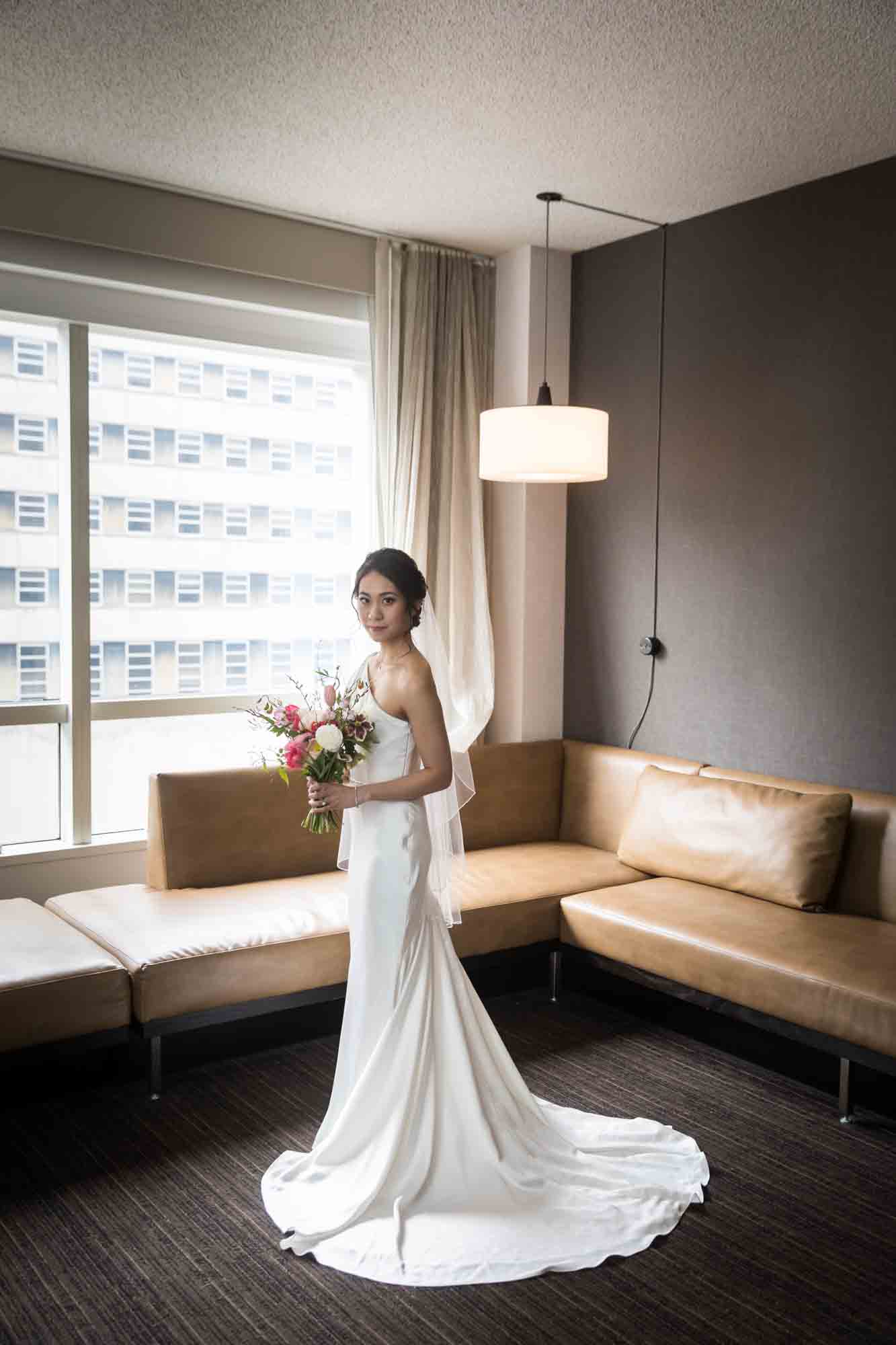 Photo of bride wearing long white dress and holding bouquet of flowers