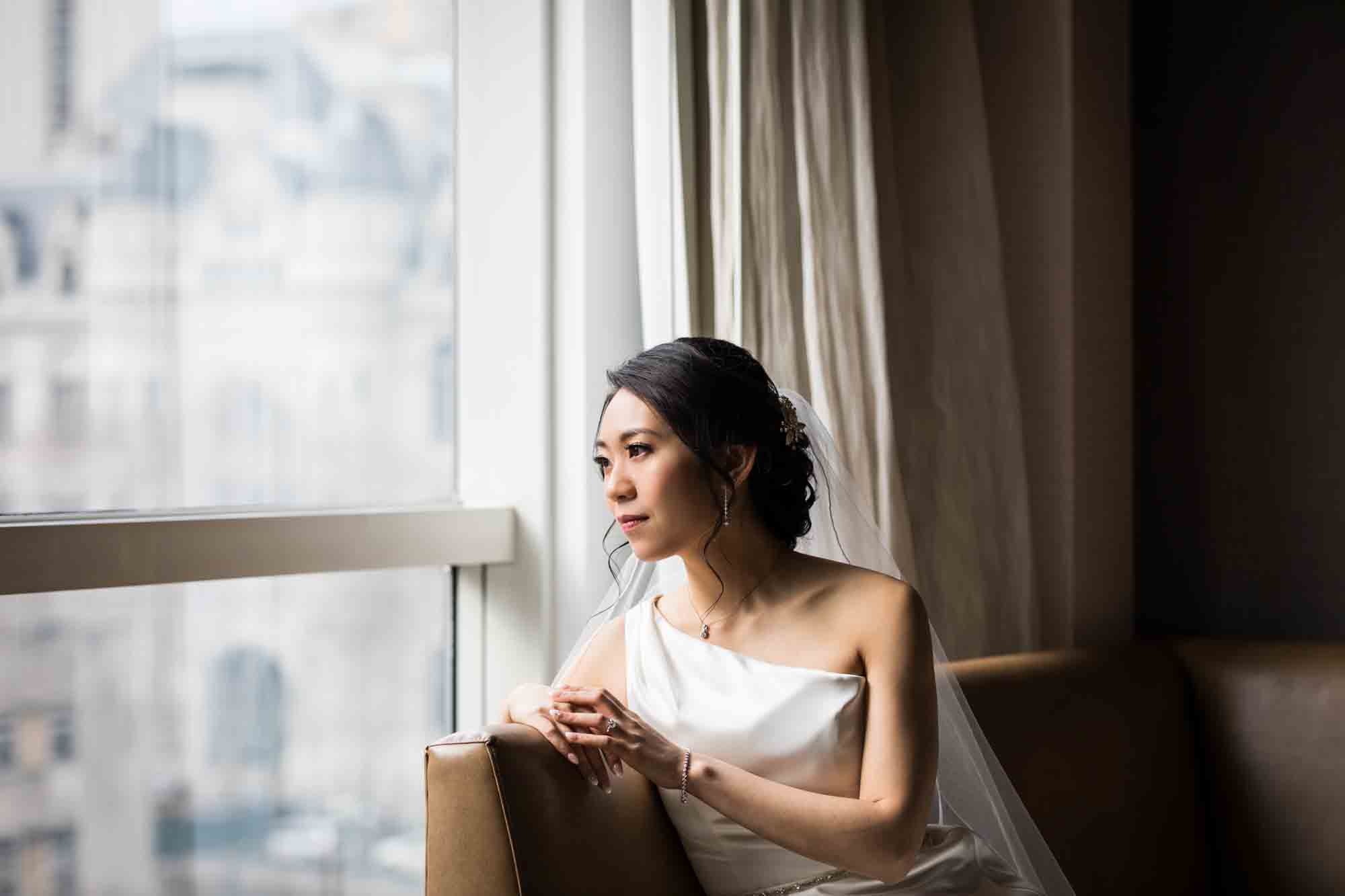 Bride laying on couch looking out window in hotel room