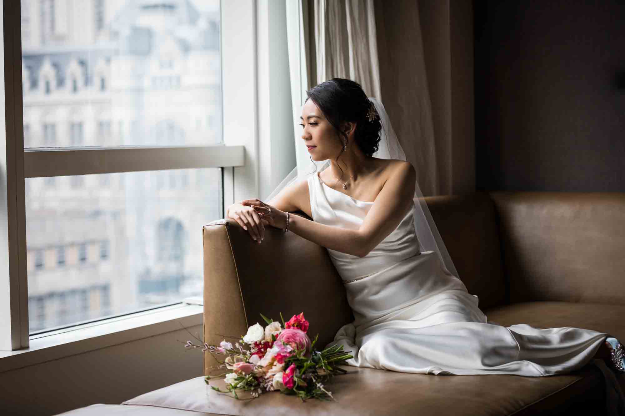 Bride laying on couch looking out window in hotel room