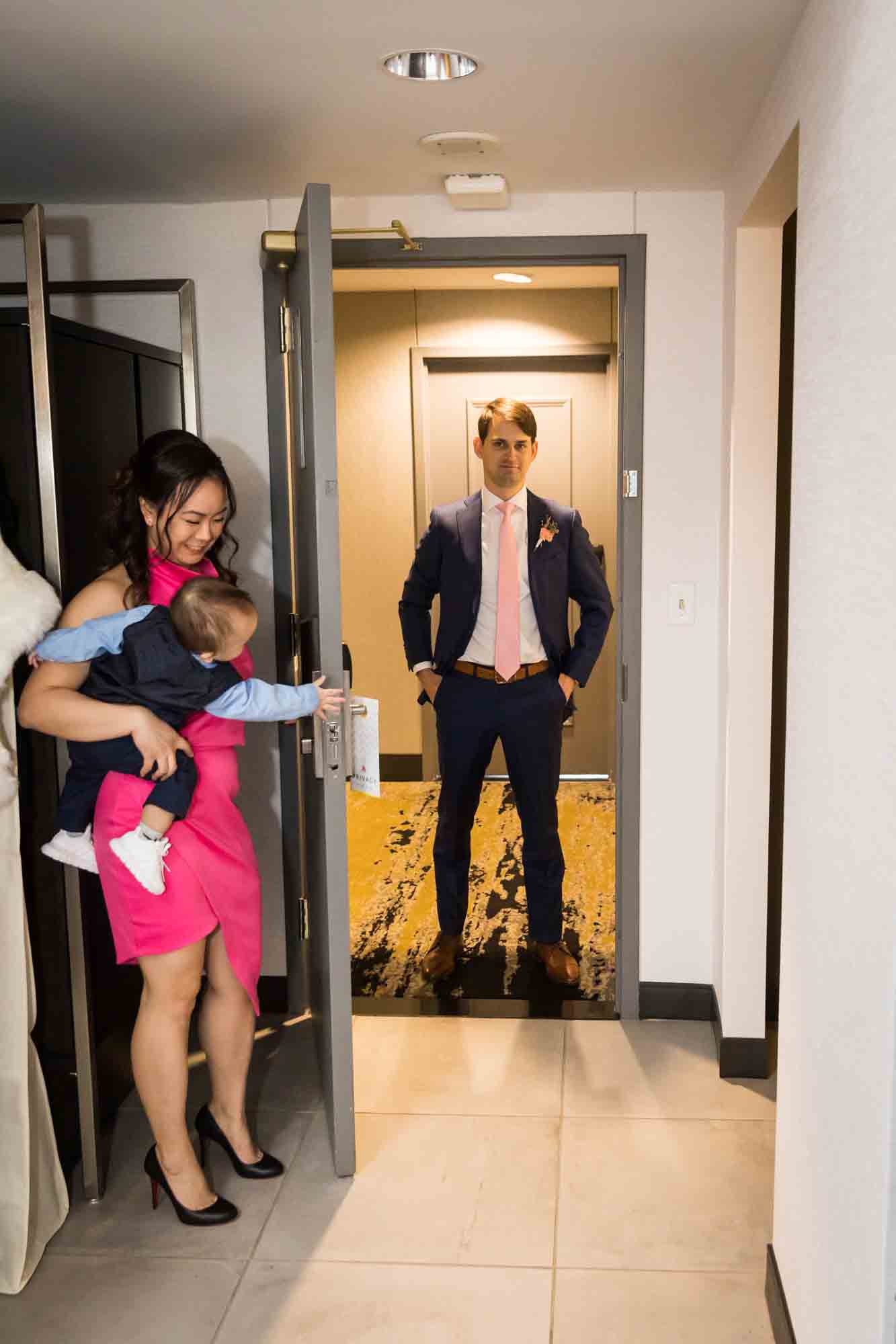 Little boy opening hotel room door for groom