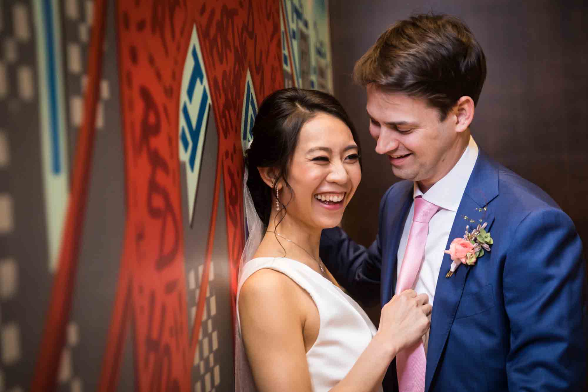 Bride and groom laughing beside graffiti mural