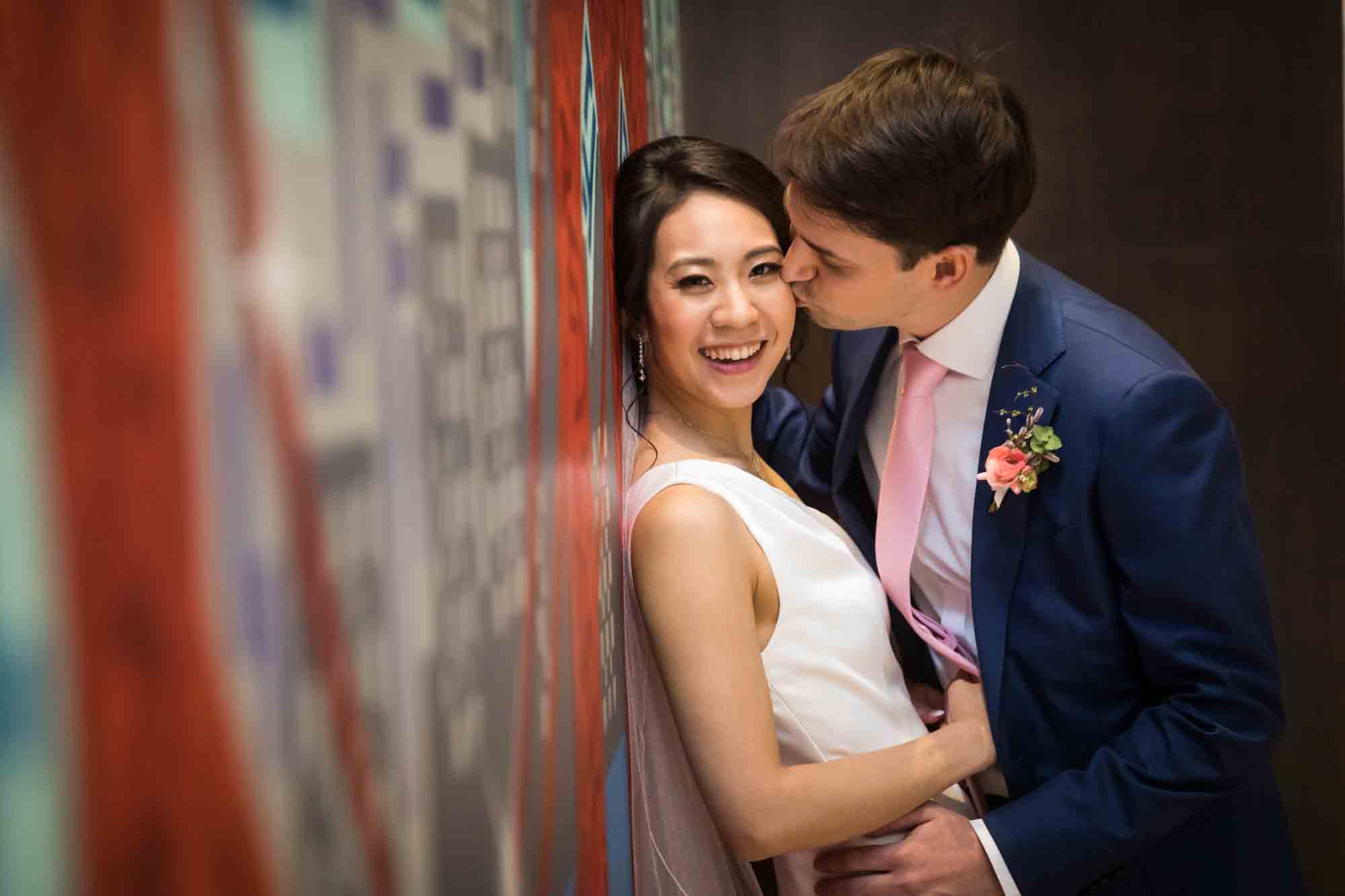 Groom kissing bride in front of graffiti wall
