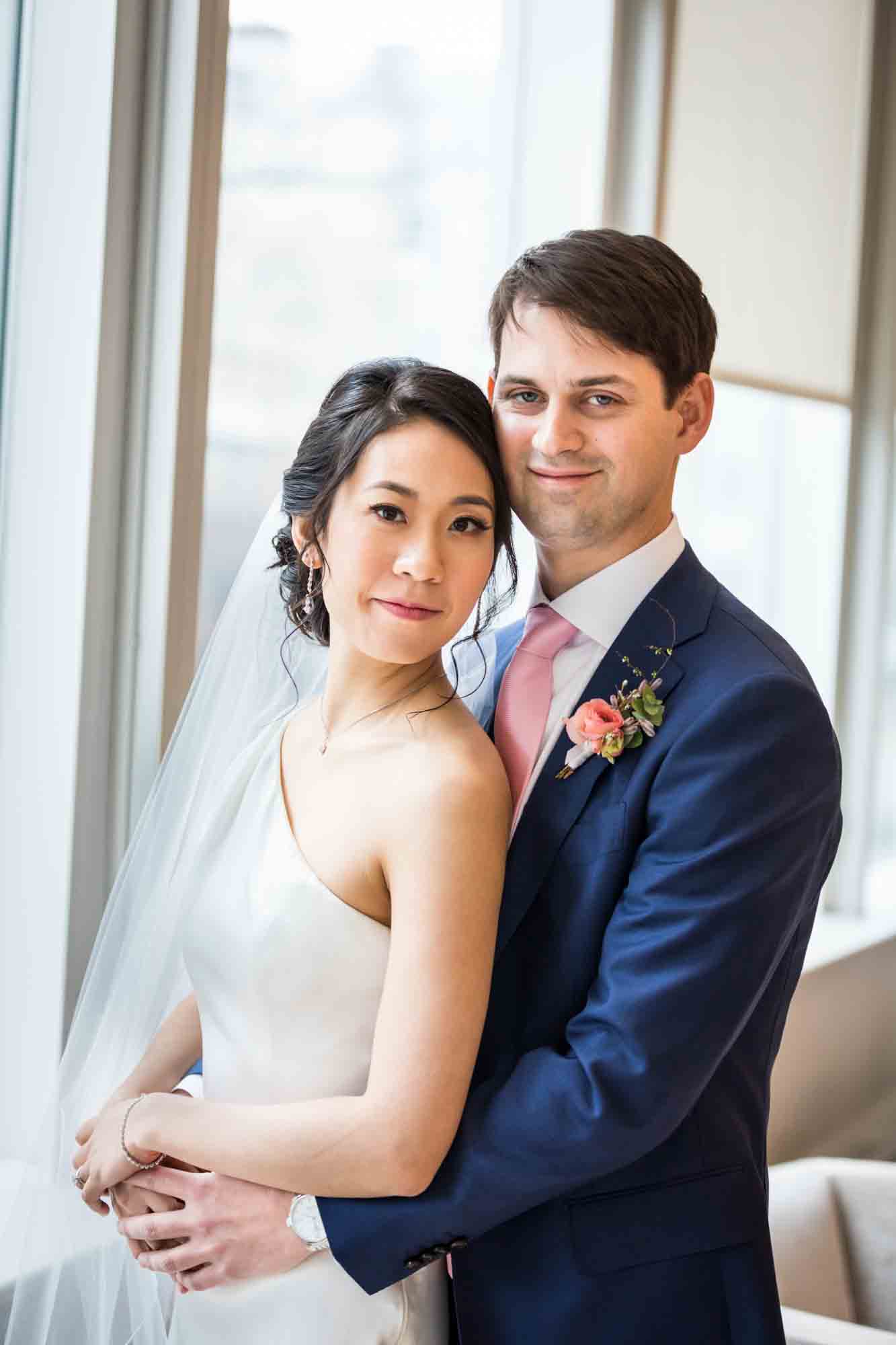 Bride and groom in front of large window