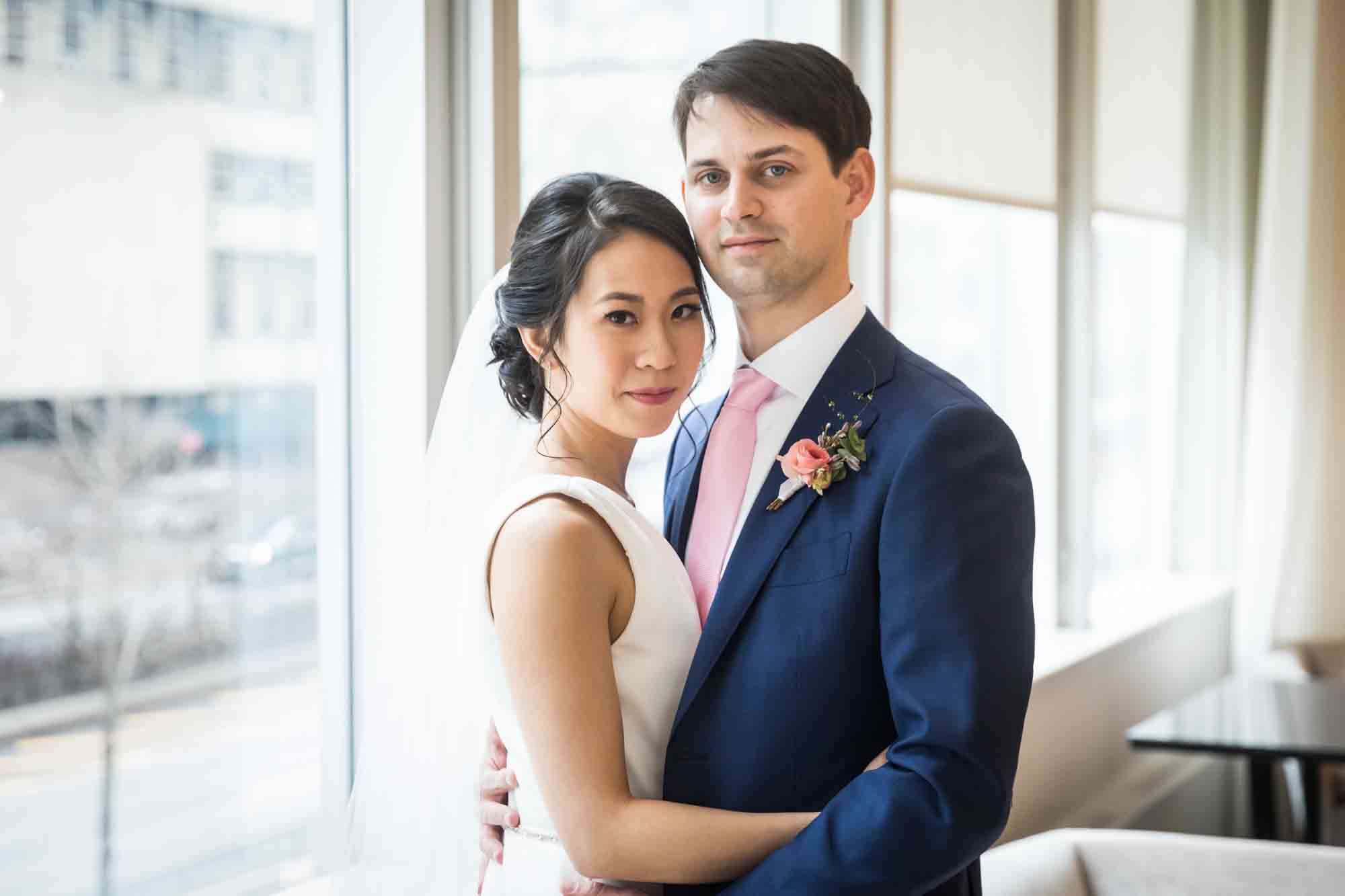 Bride and groom in front of large window