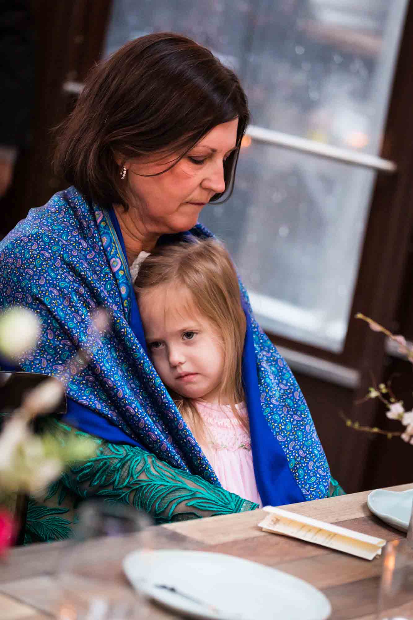 Grandmother comforting little girl at a Brooklyn restaurant wedding