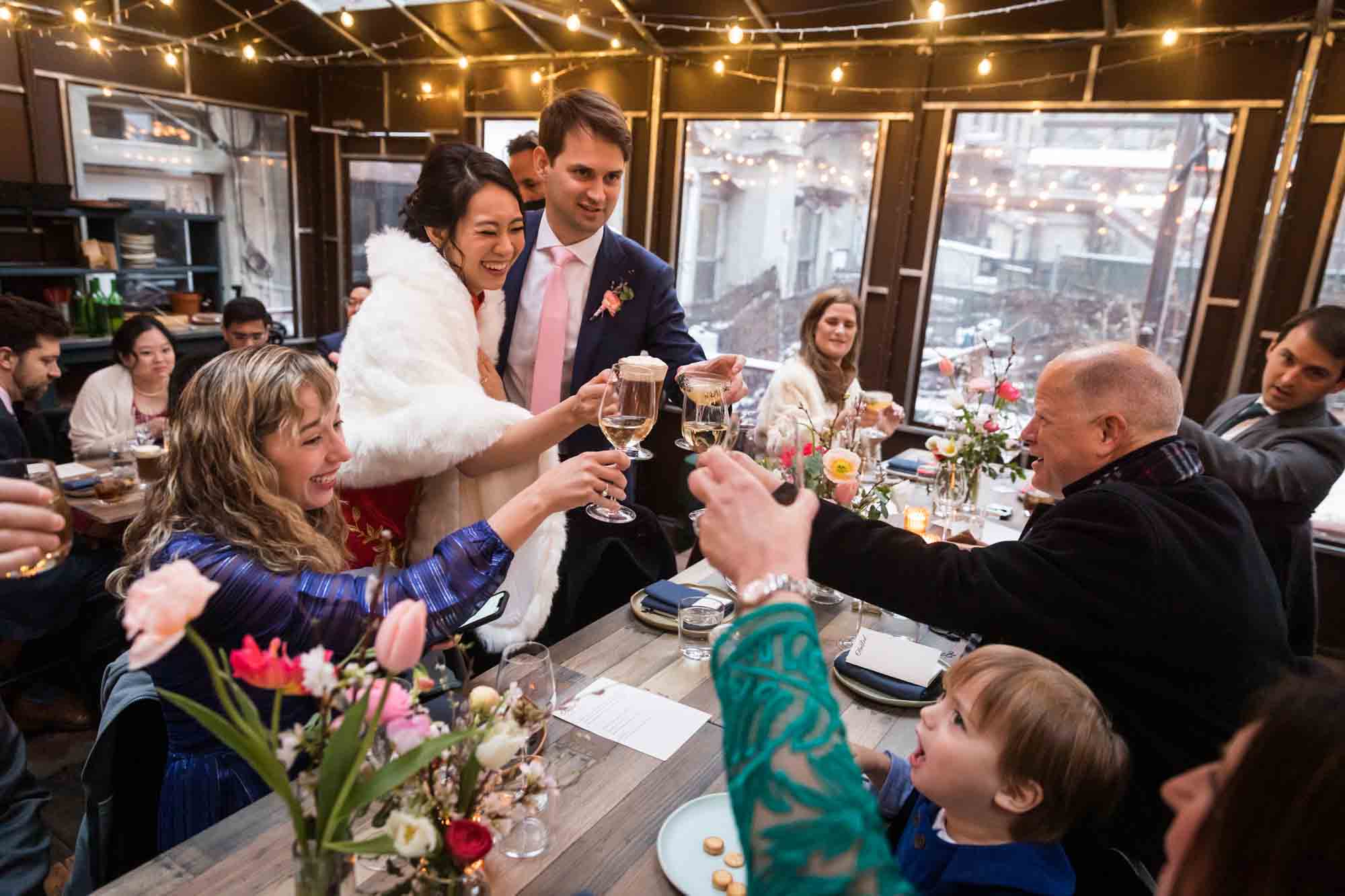 Guests toasting with glasses at a Brooklyn restaurant wedding