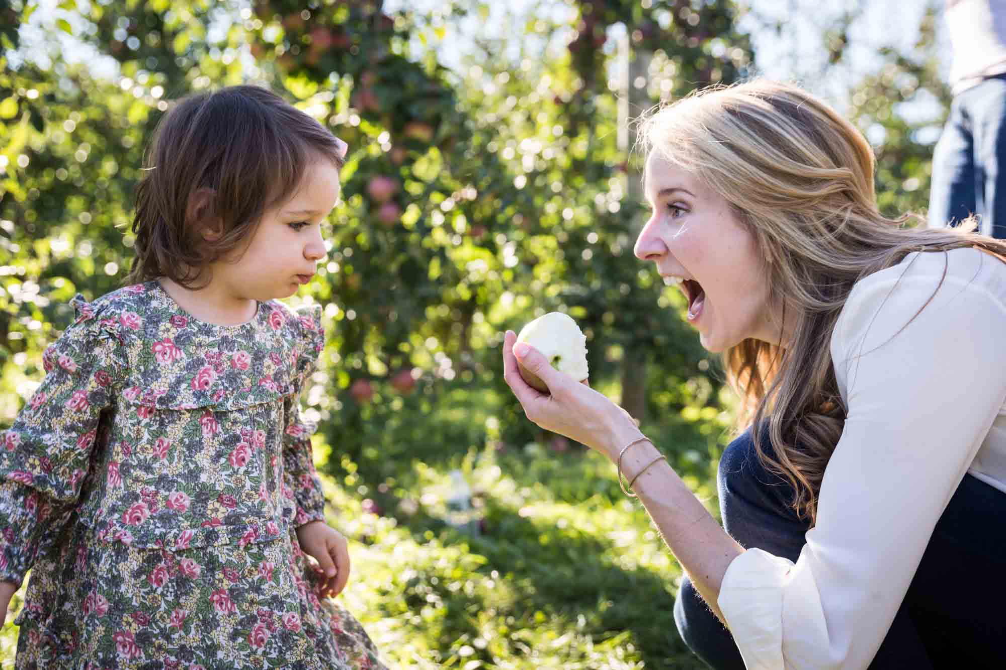 Mother about to eat apple in front of little girl
