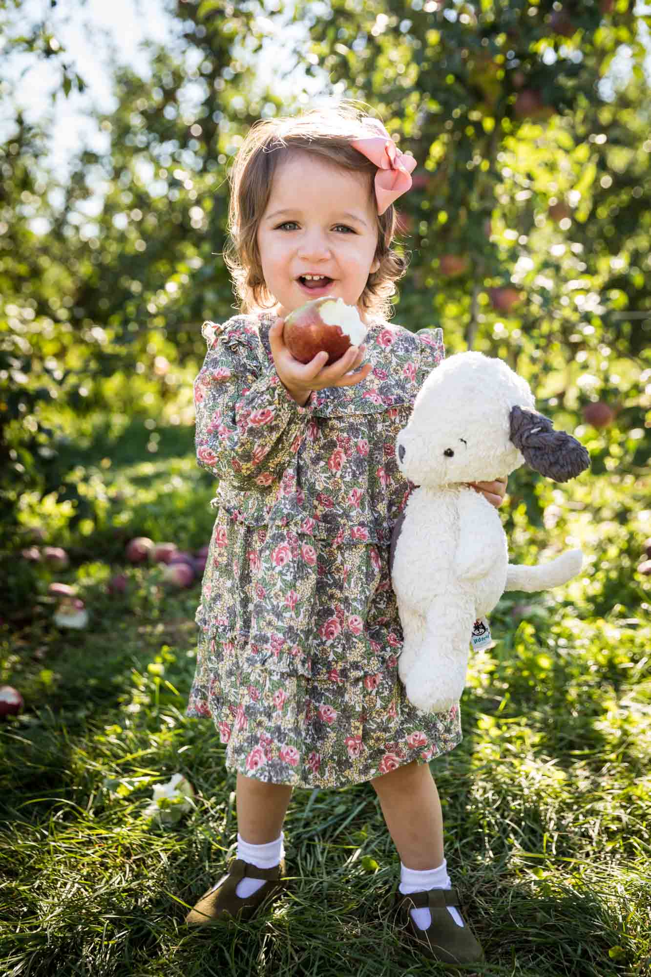 Little girl and stuffed toy dog eating apple