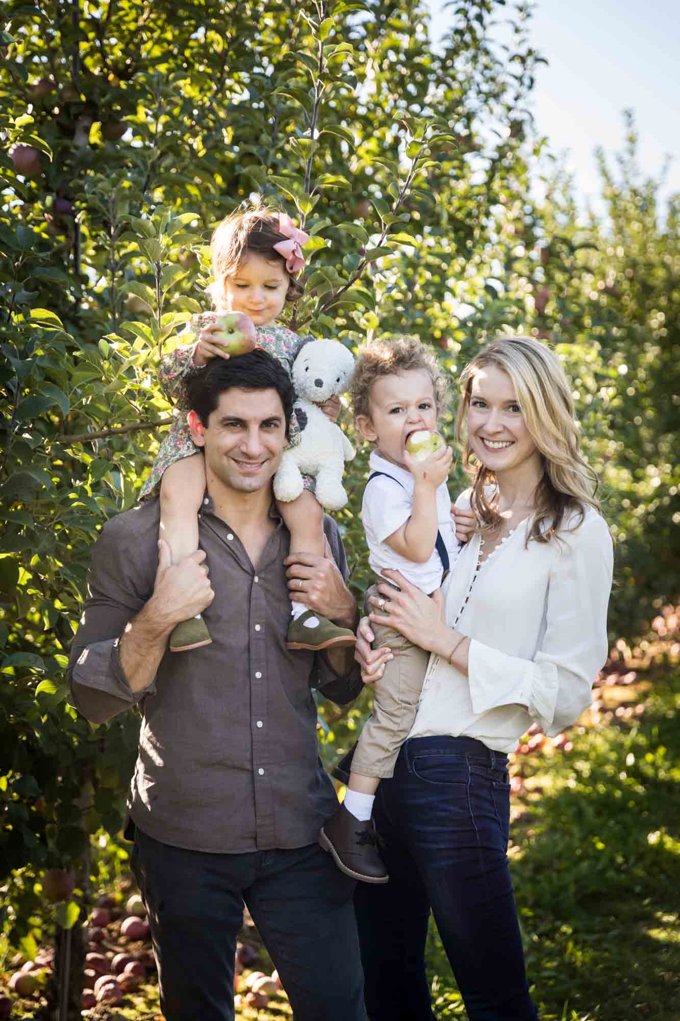 Parents holding little children in an orchard for an article on tips for apple picking family photos