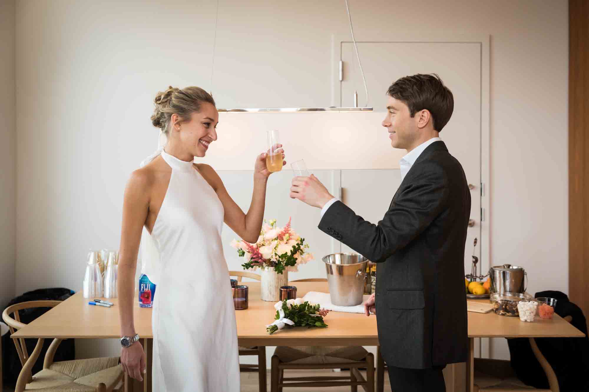 Bride and groom toasting glasses for an article on how to plan a hotel room wedding ceremony
