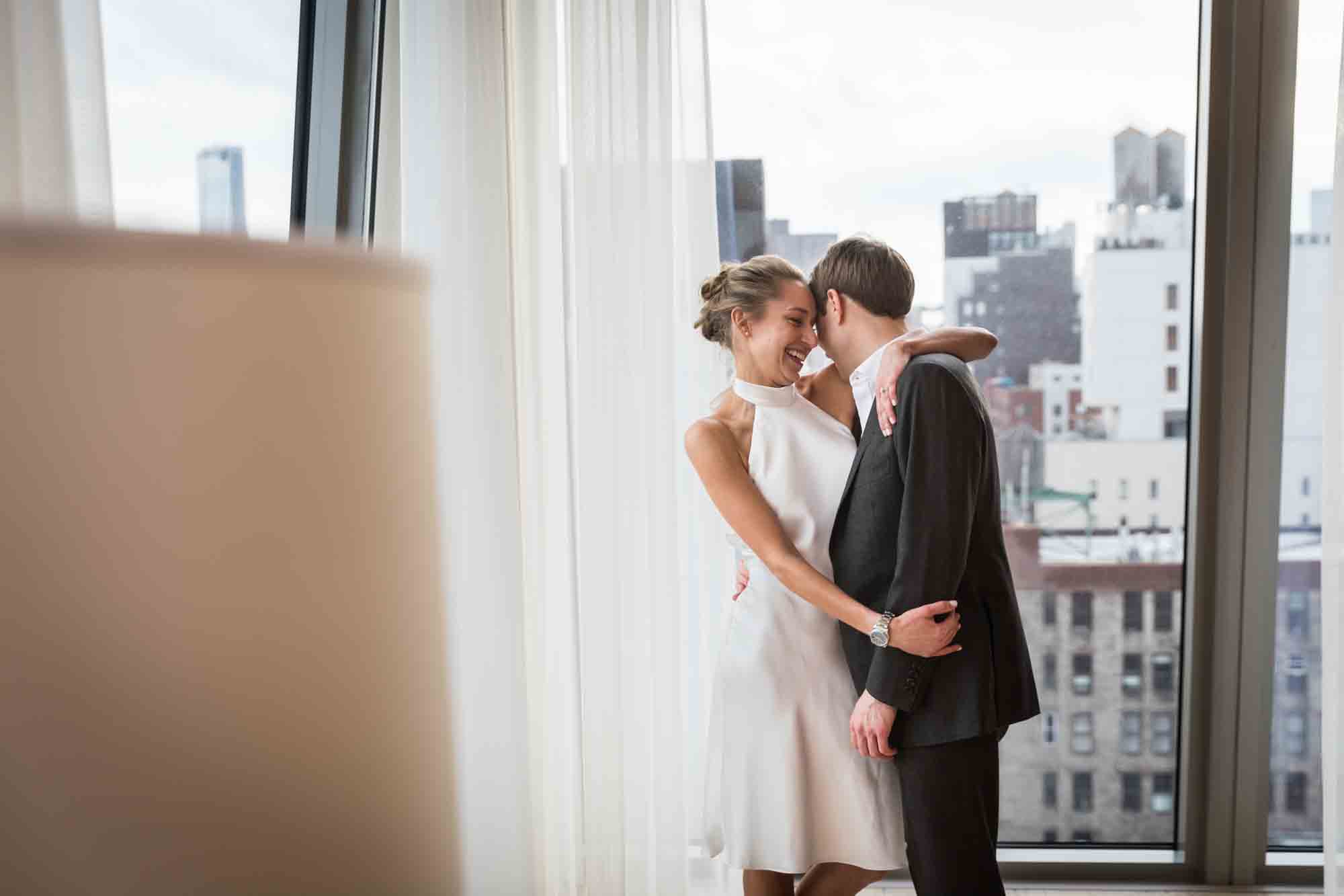 Bride and groom hugging in front of window before their Public Hotel wedding