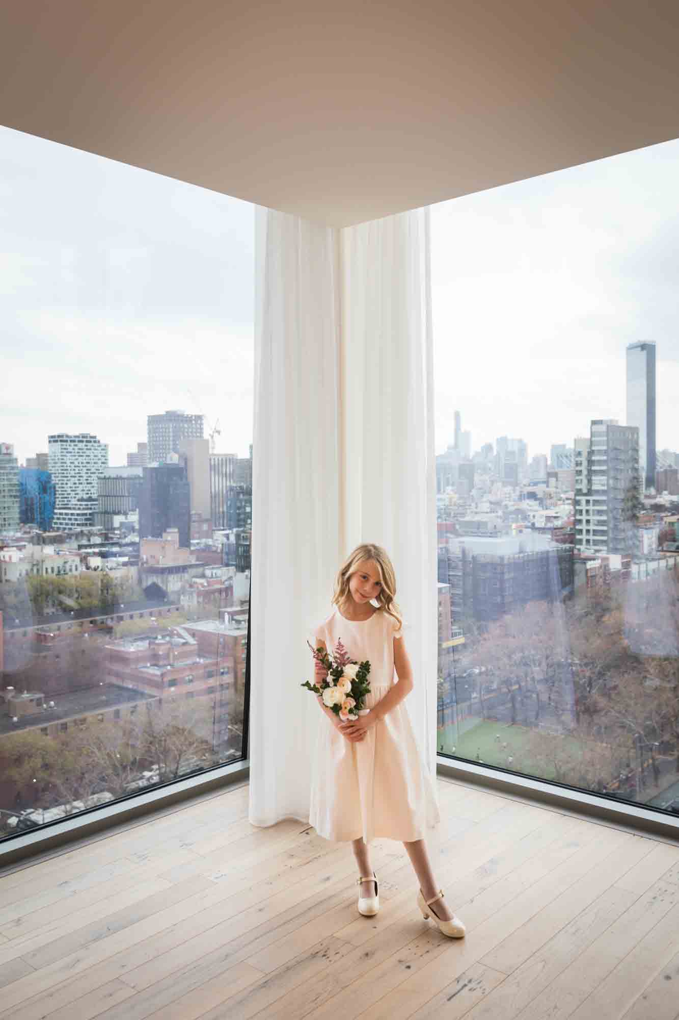 Little flower girl standing in front of window before a Public Hotel wedding