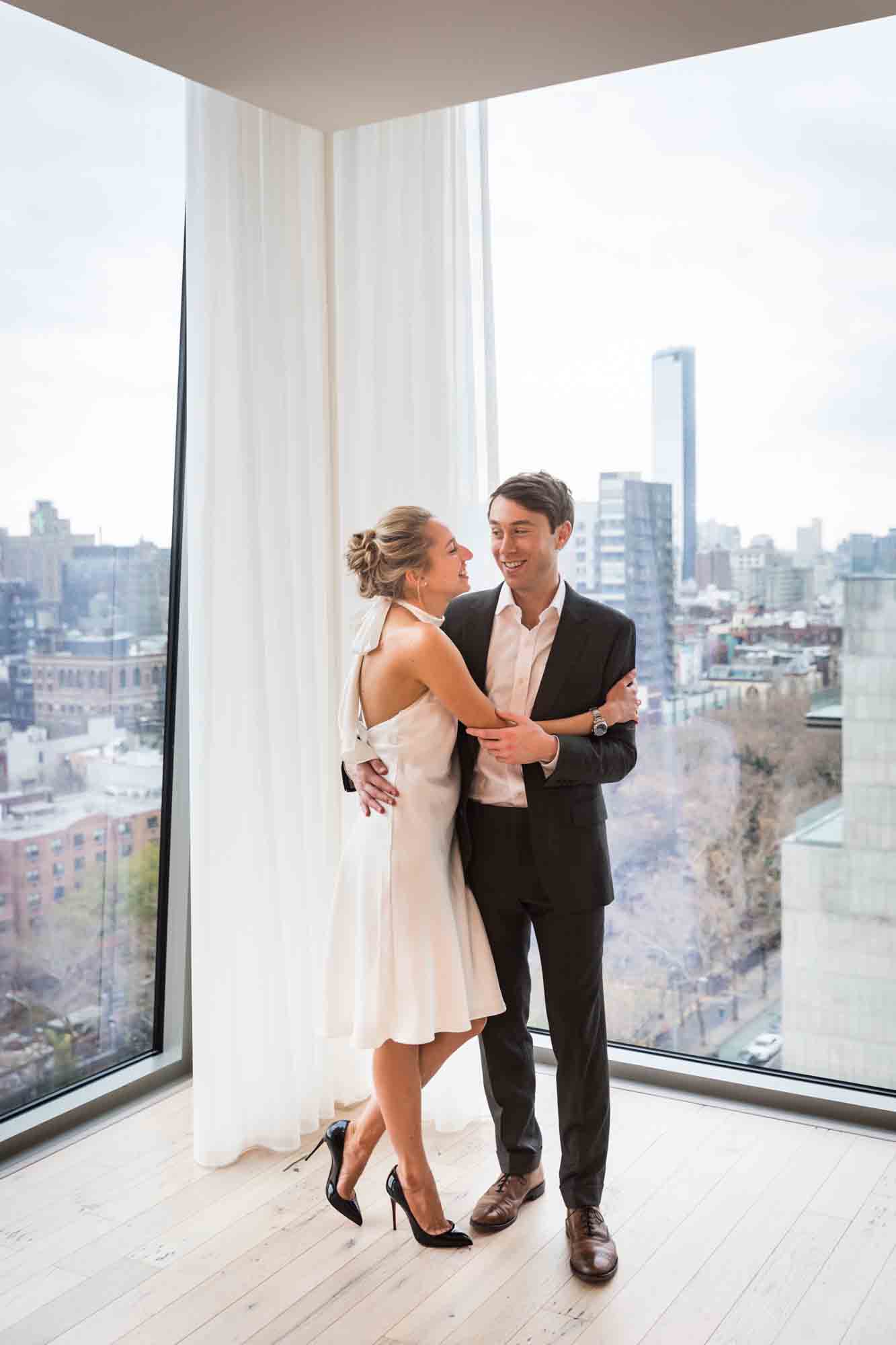 Couple hugging in front of windows 
