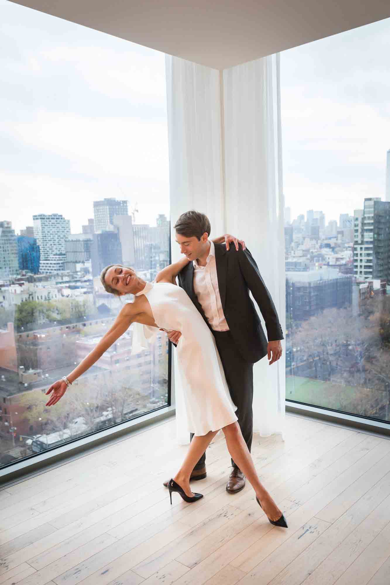 Man holding woman in dance move in front of windows
