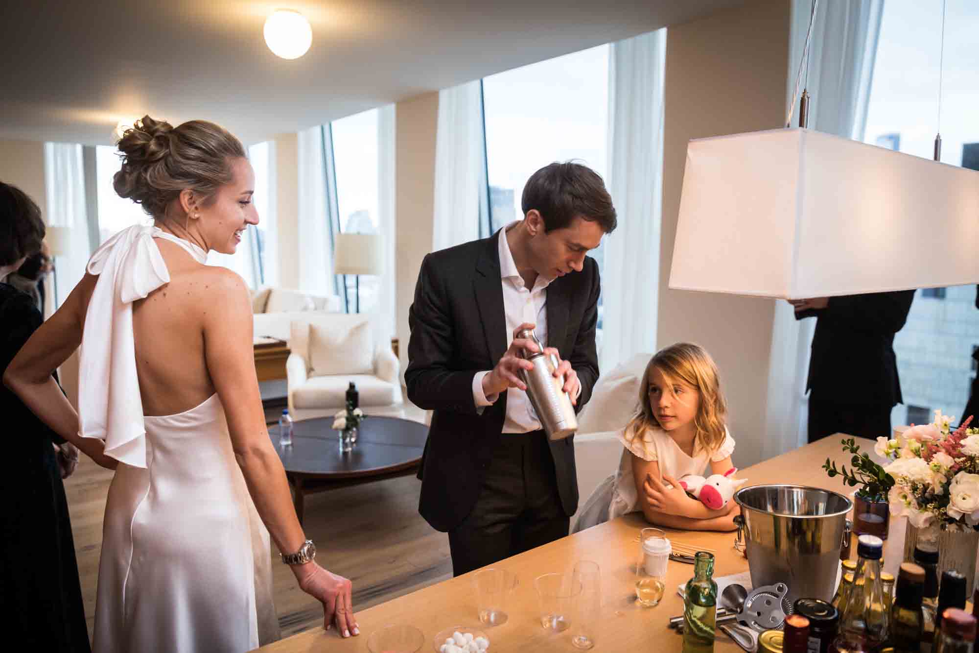 Groom showing martini shaker to little girl and bride for an article on how to plan a hotel room wedding ceremony