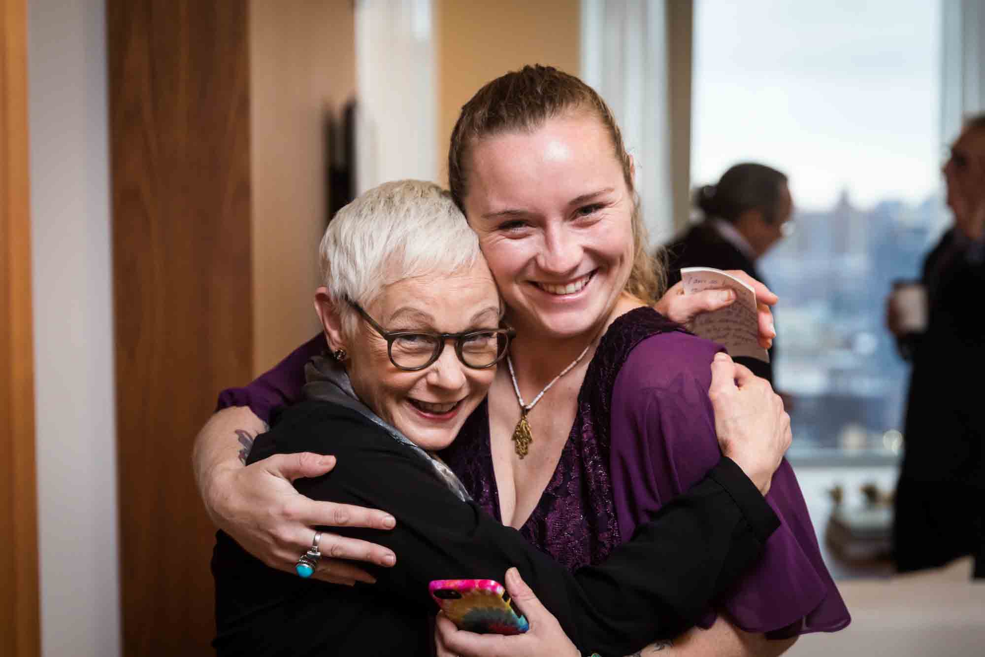 Two female guests hugging and smiling at a Public Hotel wedding