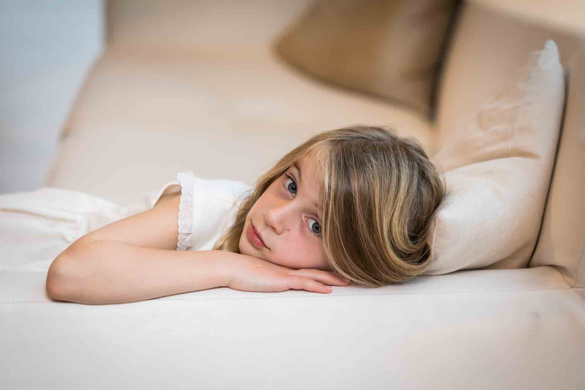 Little girl lying on white couch at a Public Hotel wedding